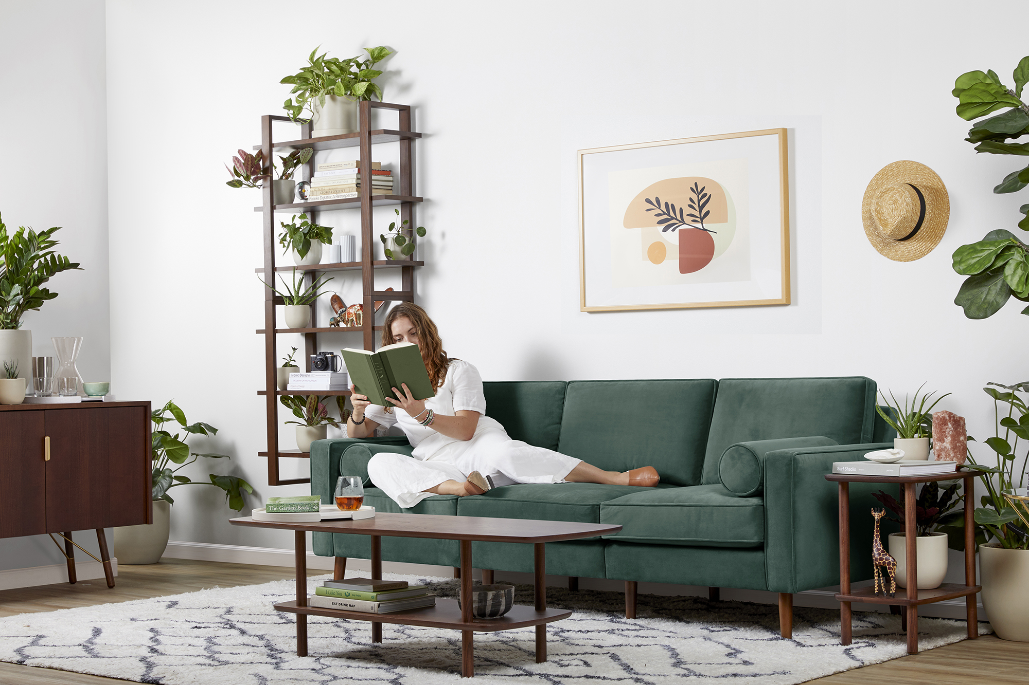 A woman reading a green book on a green couch in her living room