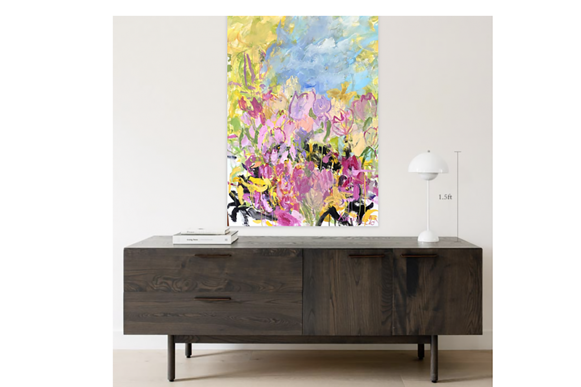 A painting of pastel flowers on a white wall above a brown table 
