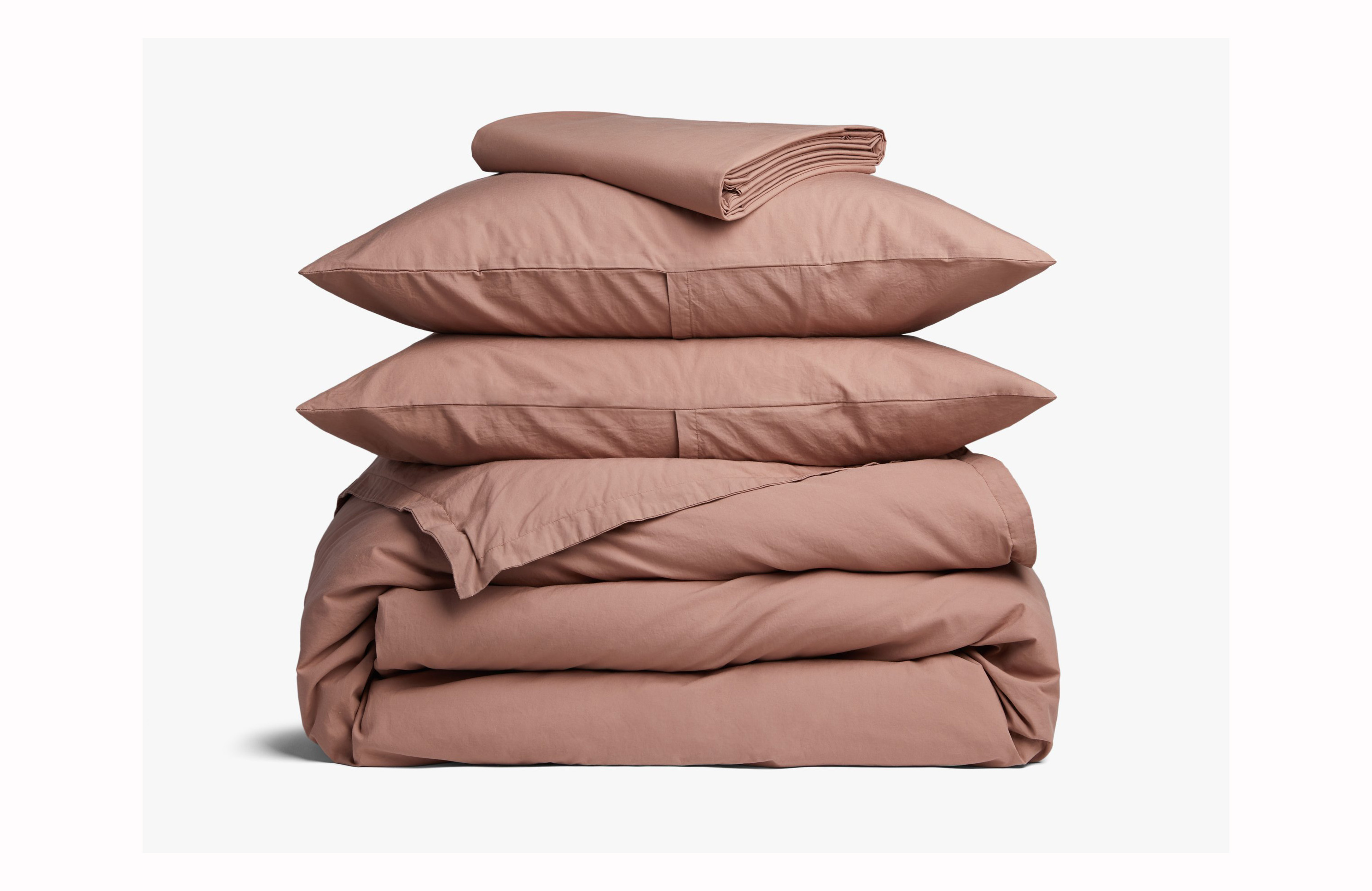 A stack of pillows and blankets in a rose pink color 
