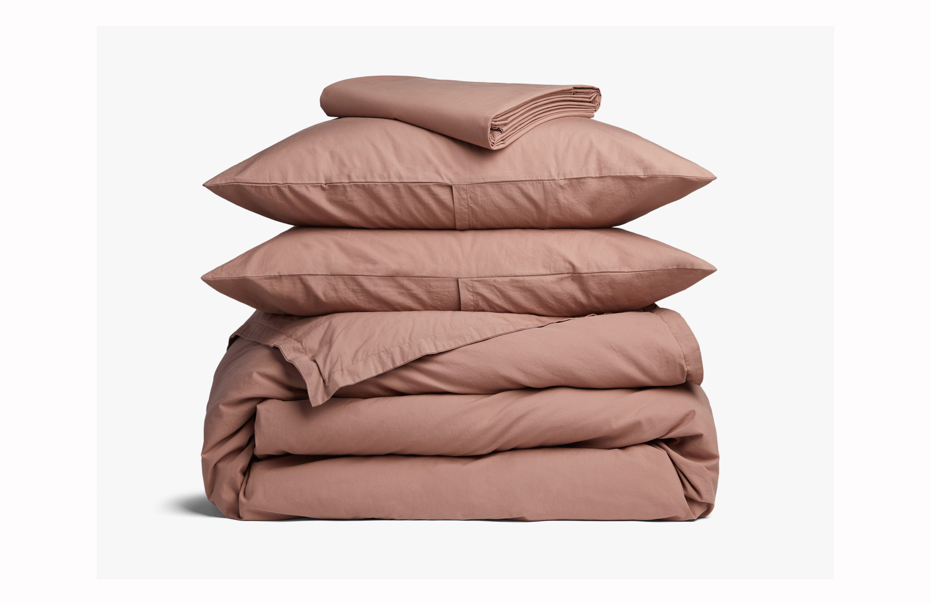 A stack of pillows and blankets in a rose pink color