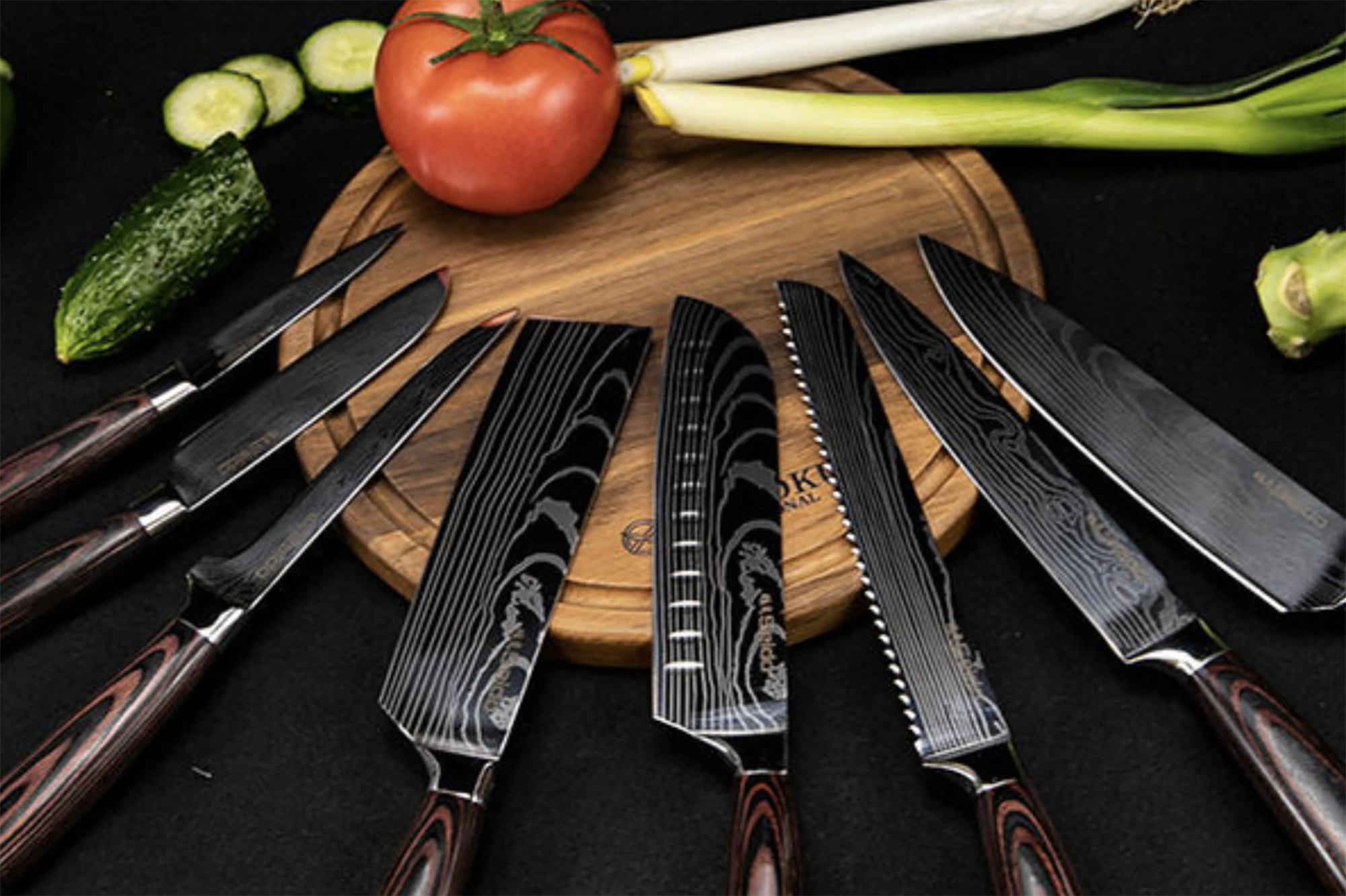 A set of wood handle knives on a wooden cutting board with a tomato and green onions.