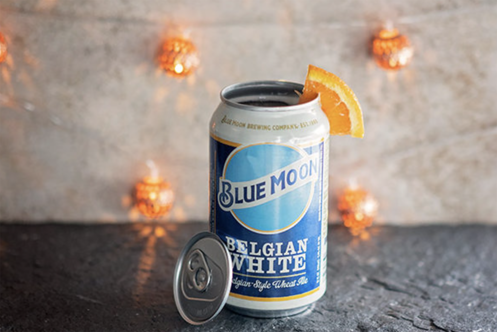 A can of Blue moon with the cap cut off and an orange wedge in the can