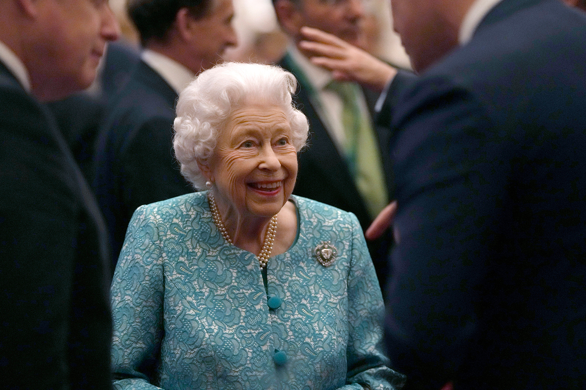 Queen Elizabeth wearing light blue and no hat while chatting with a guest