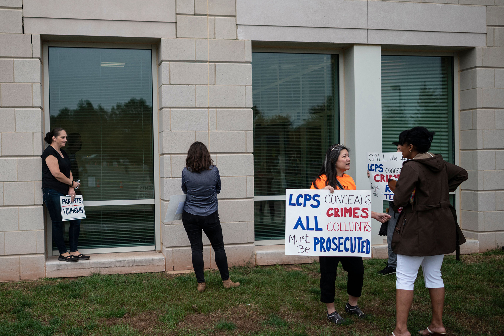 Protesters and activists hold signs as they stand outside a Loudoun County Public Schools (LCPS) board meeting in Ashburn, Virginia on October 12, 2021.