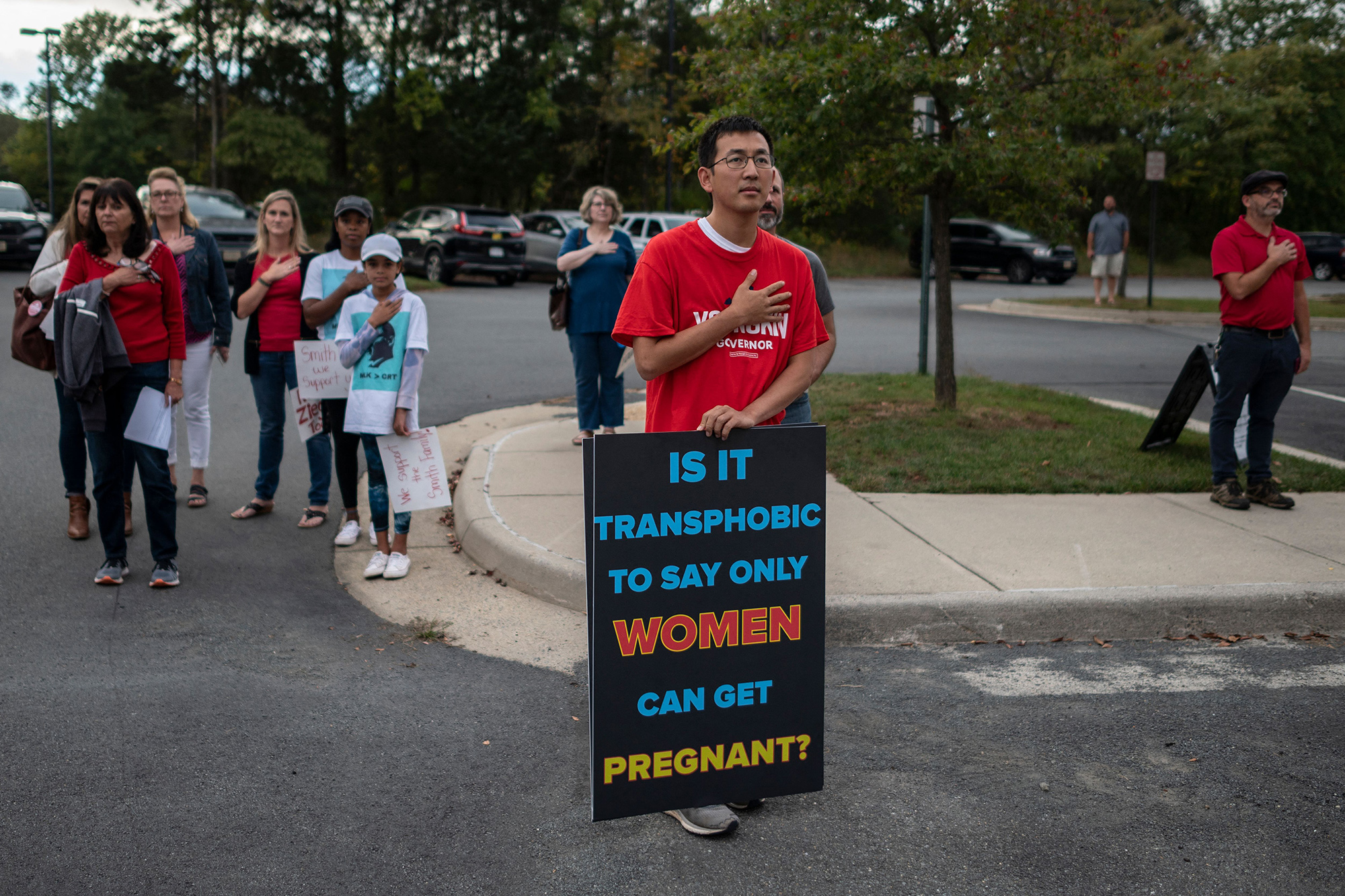 Protesters and activists stand at attention as the national anthem is sung to open a Loudoun County Public Schools (LCPS) board meeting in Ashburn, Virginia on October 12, 2021.