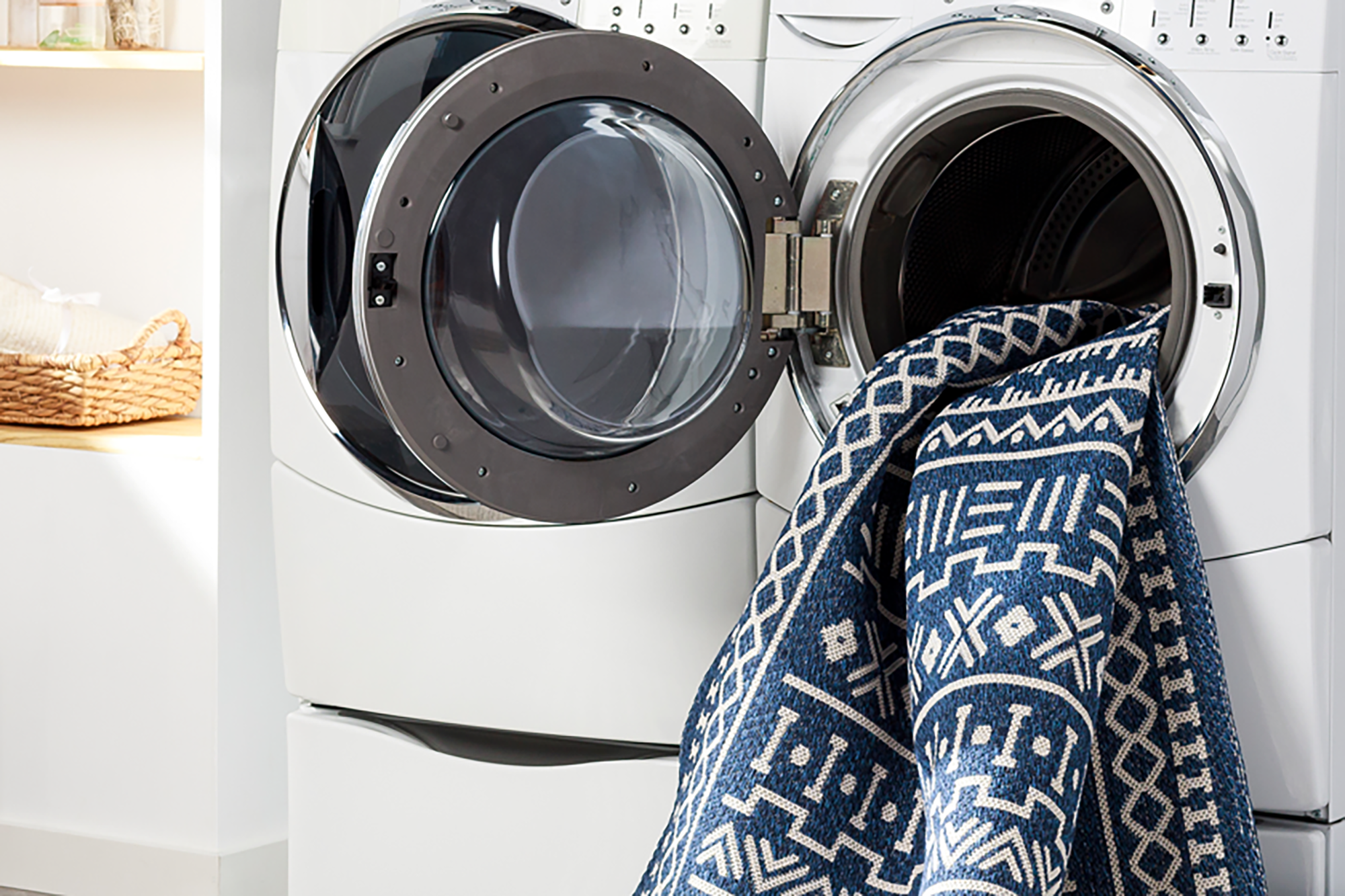 A blue rug being put in the washing machine 