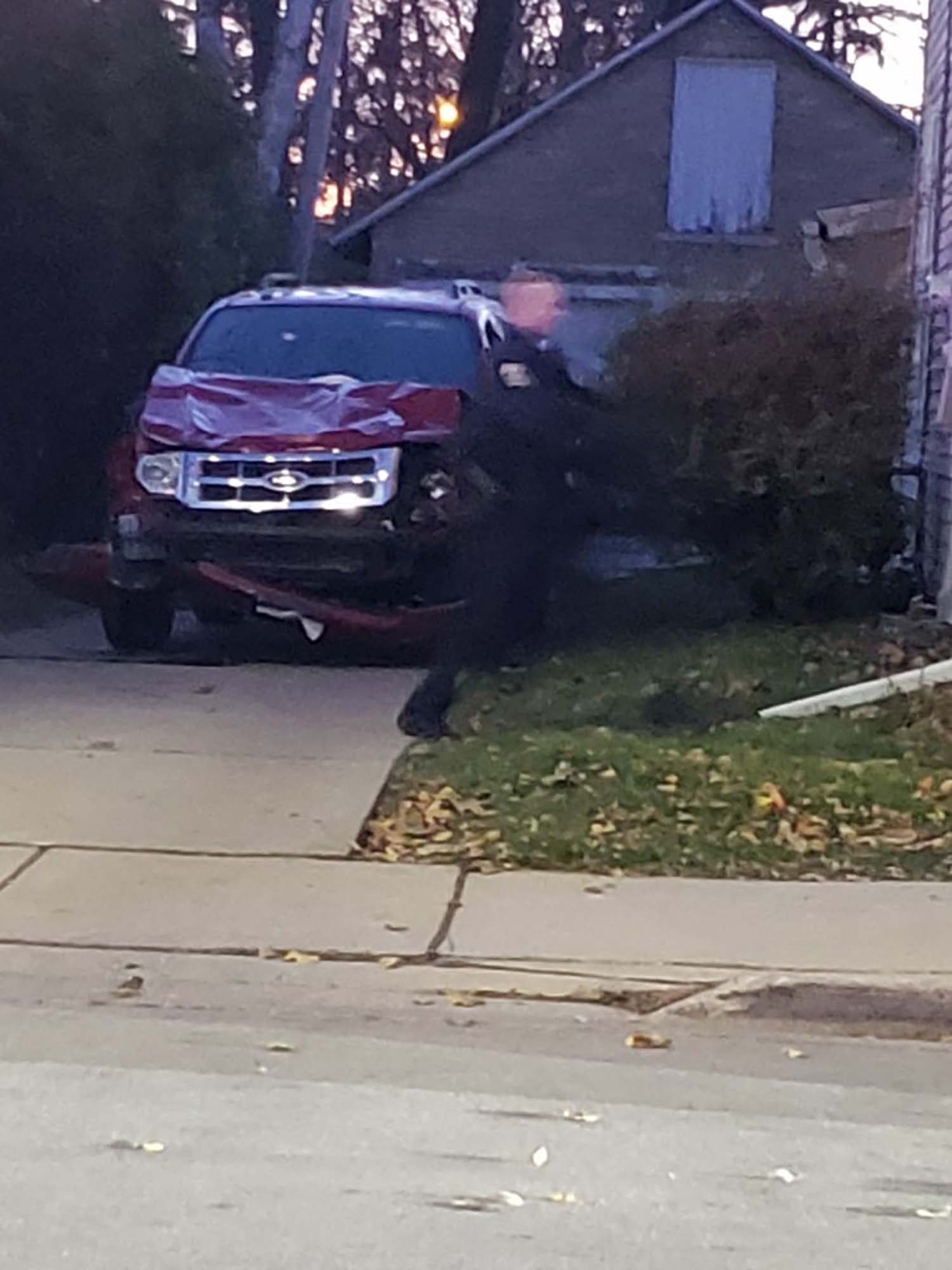 A police officer stands near a dented red SUV that may have been the one involved in the holiday parade incident.