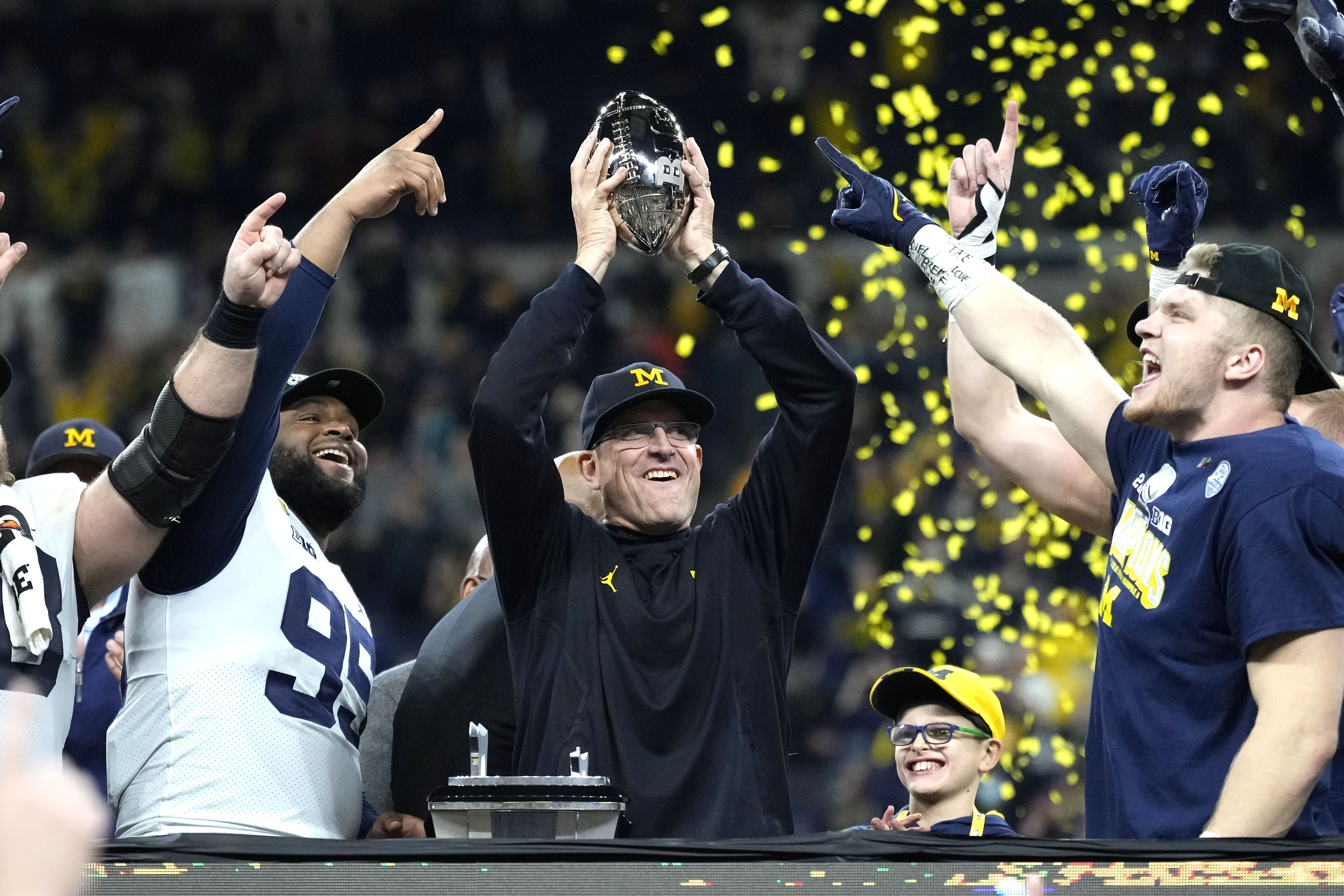 Michigan coach Jim Harbaugh and his players celebrate after their 42-3 win over Iowa in the Big Ten title game.