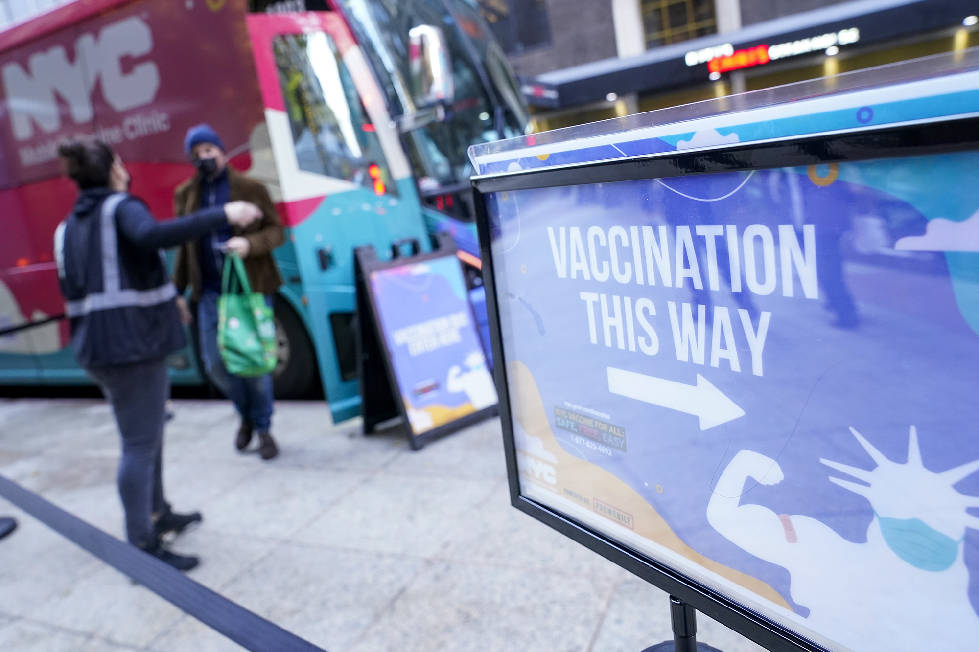 health care worker, right, directs a man who was just vaccinated to an observation area at NYC mobile vaccine clinic in Midtown Manhattan, Monday, Dec. 6, 2021