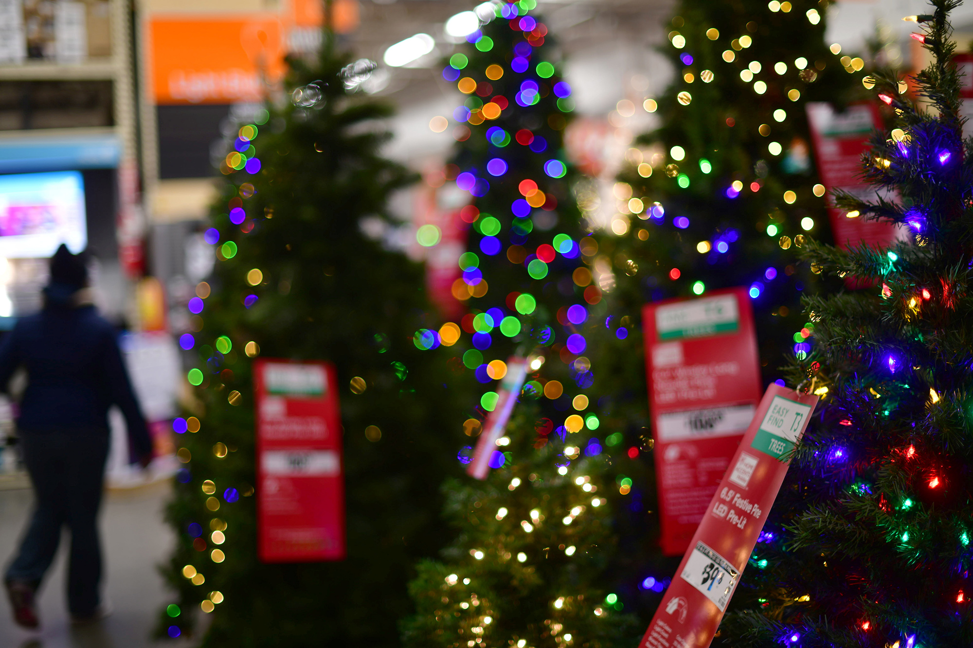 A shopper walks past artificial Christmas trees 
