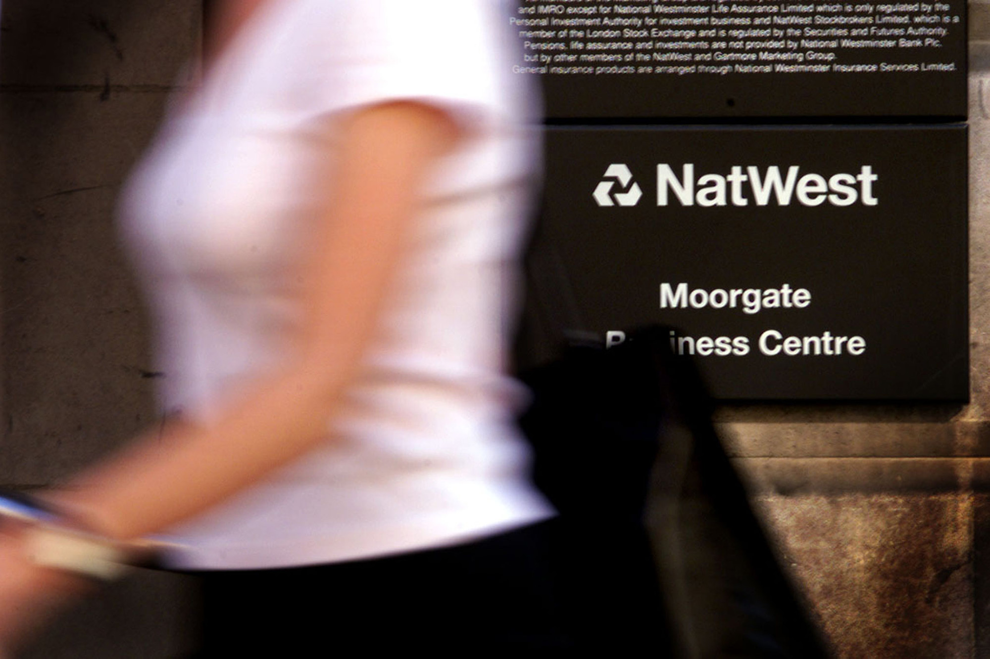 A woman walks past a NatWest bank branch