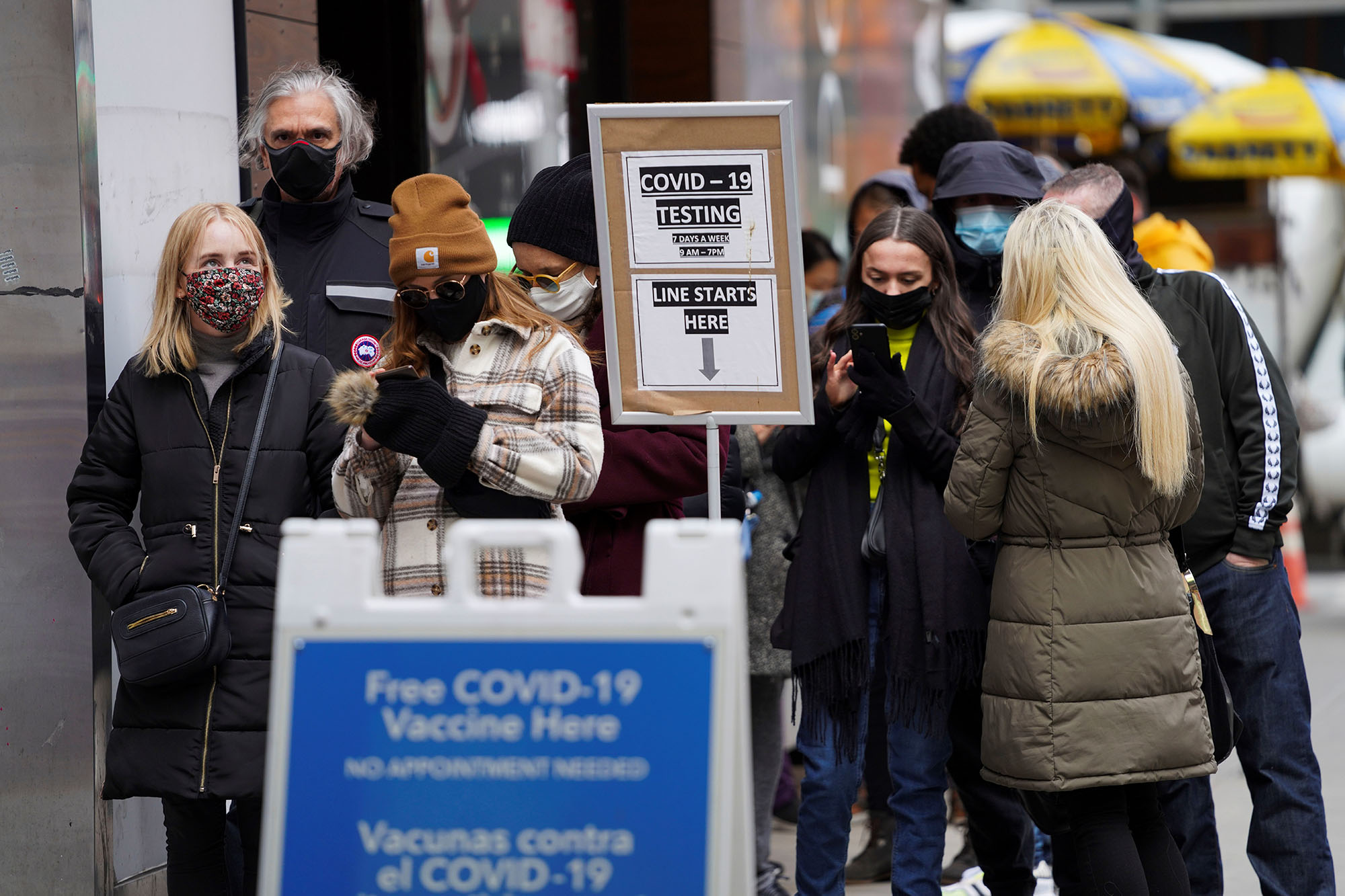 People wait to enter a COVID-19 test and vaccination site.