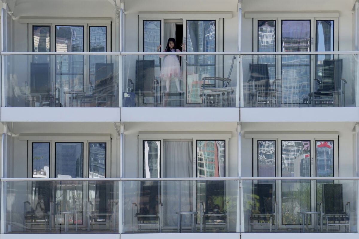 A passenger waves from the Spectrum of the Seas cruise ship docked at Kai Tak cruise terminal in Hong Kong on Jan. 5, 2022. 