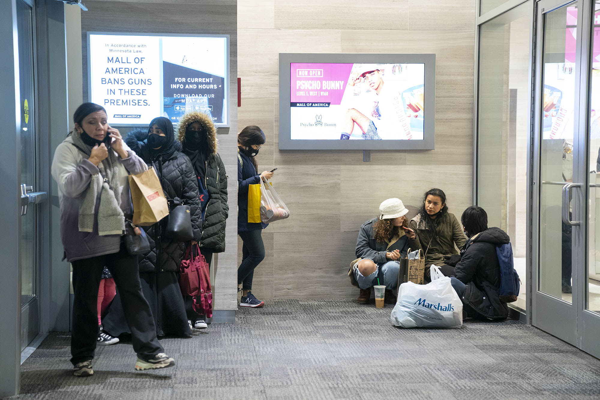 People wait near an exit to be picked up from the Mall of America following a shooting, where two people were wounded.